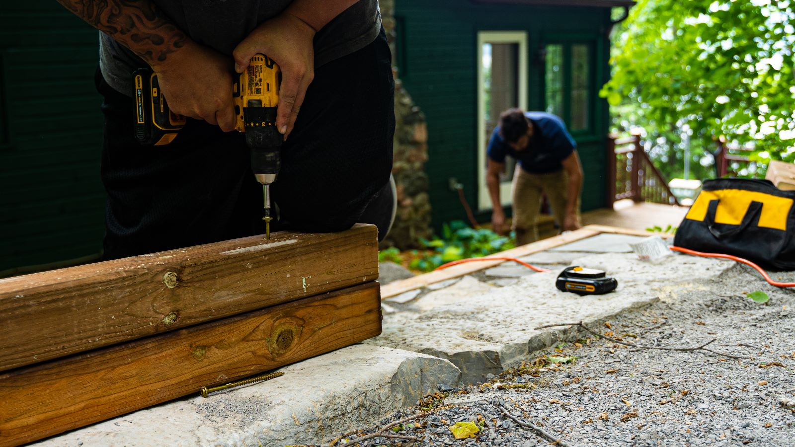 Person using drill to fasten wooden boards outdoors