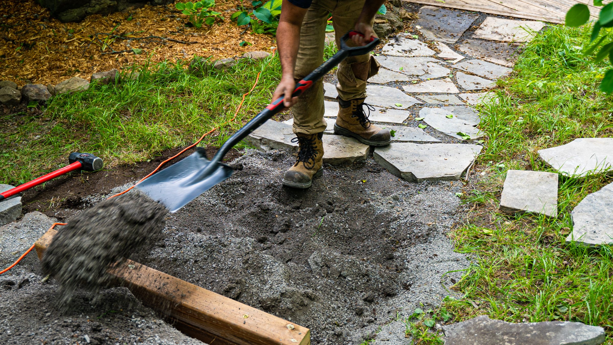 Person shoveling gravel onto garden pathway