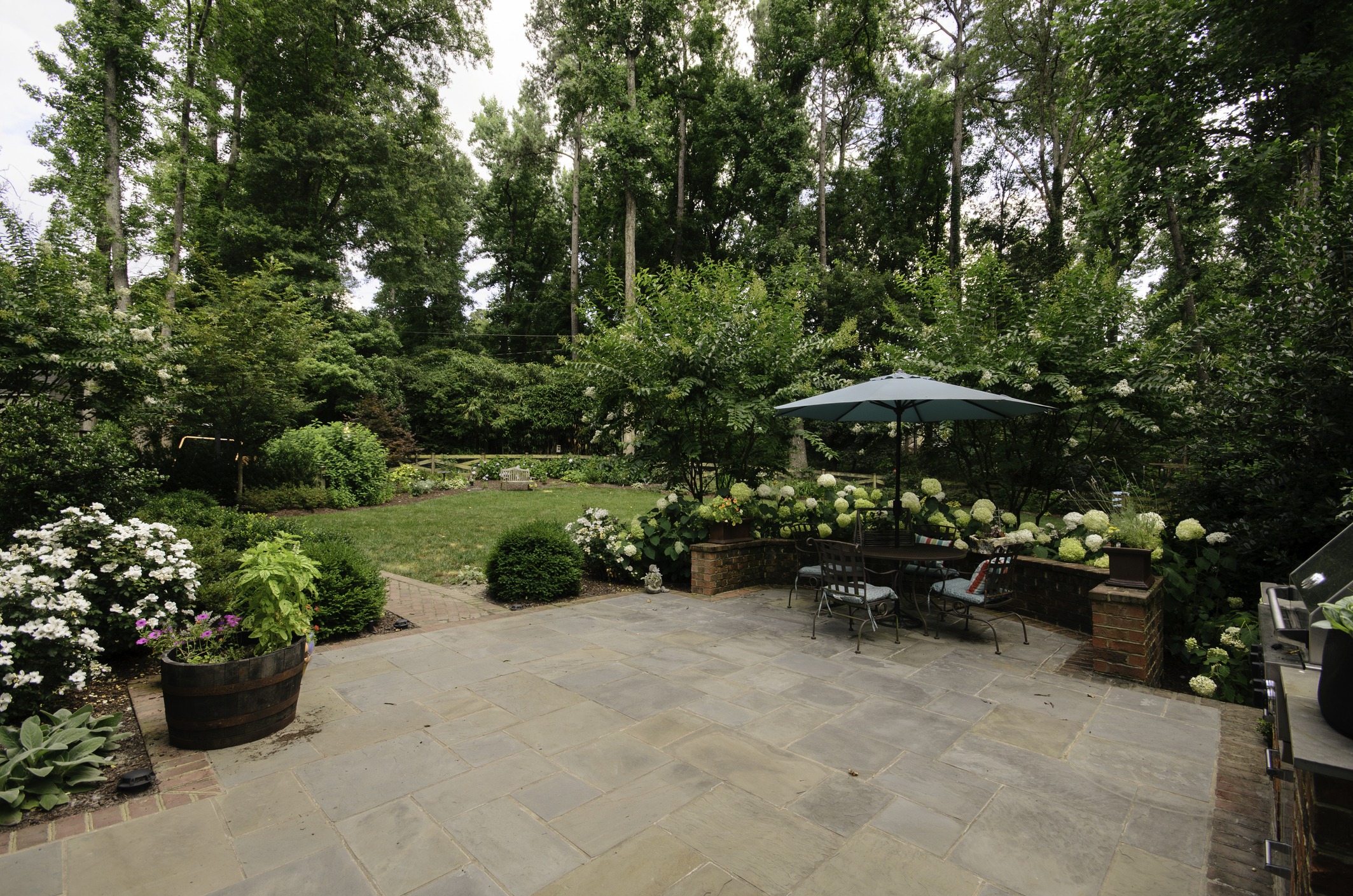 Landscaped backyard patio with umbrella and garden