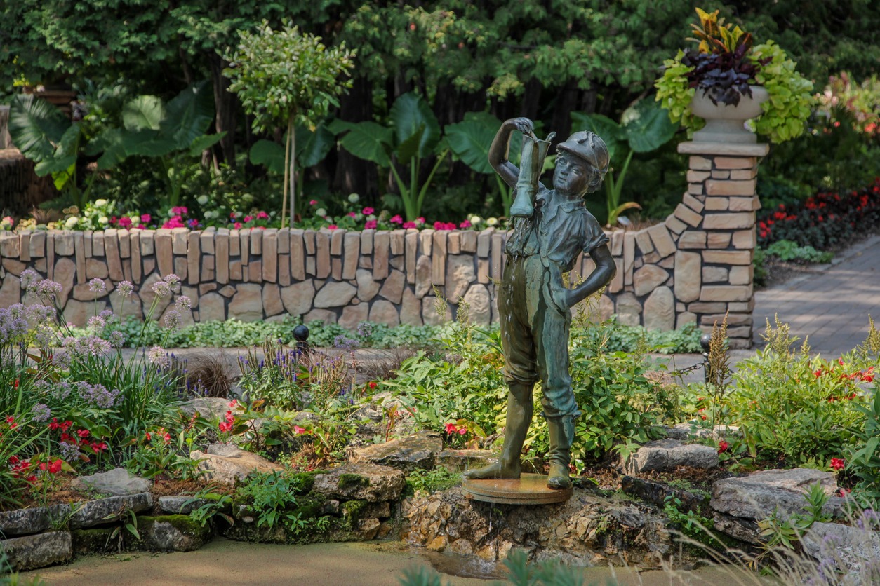 Bronze boy statue holding fish in garden pond