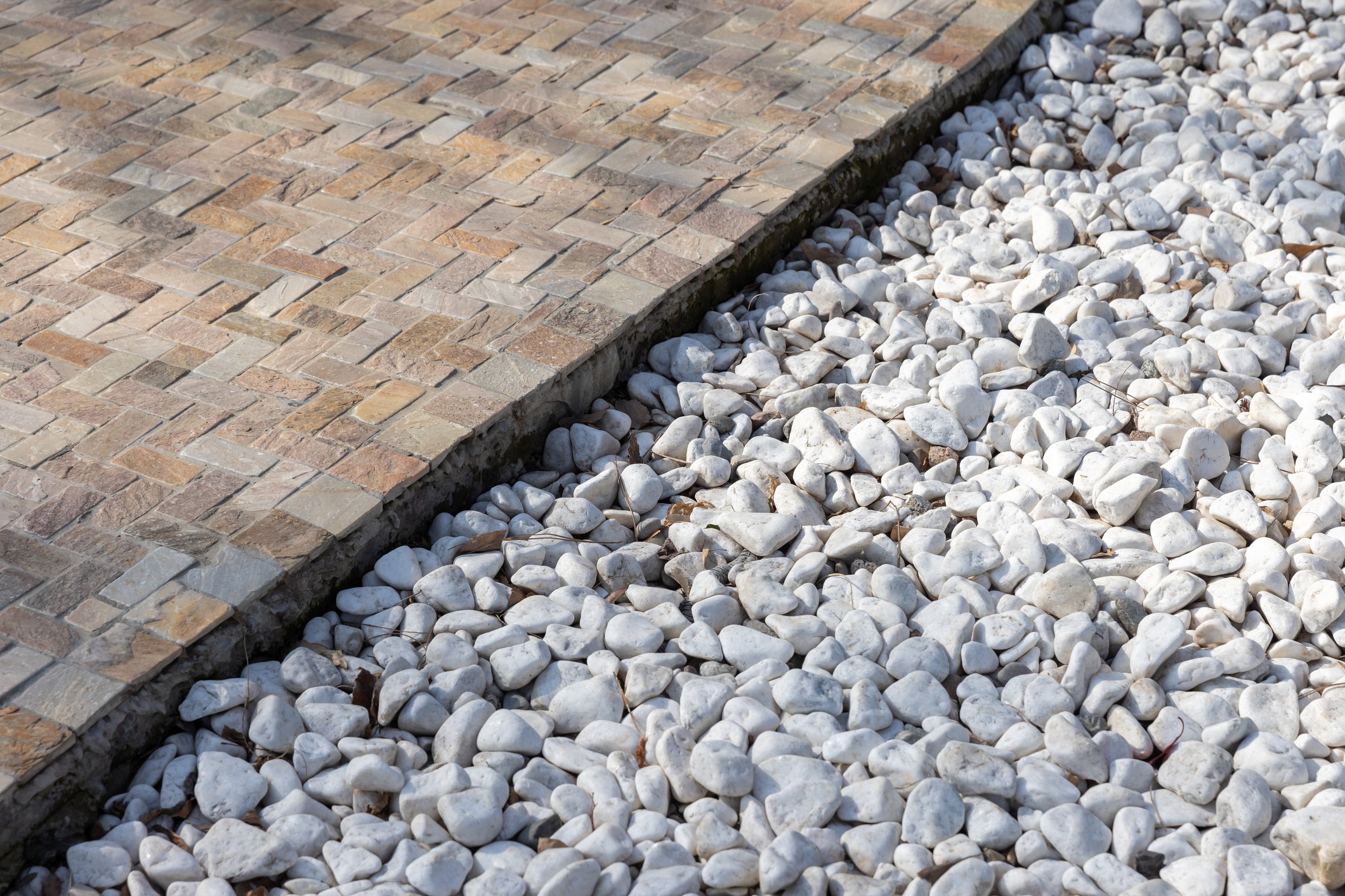 Stone walkway beside white landscaping pebbles