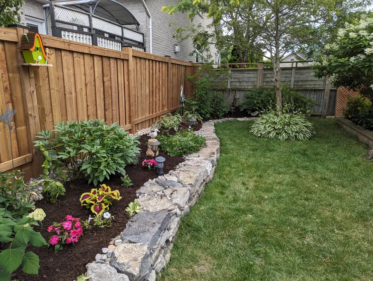 Backyard garden with stone border and wooden fence