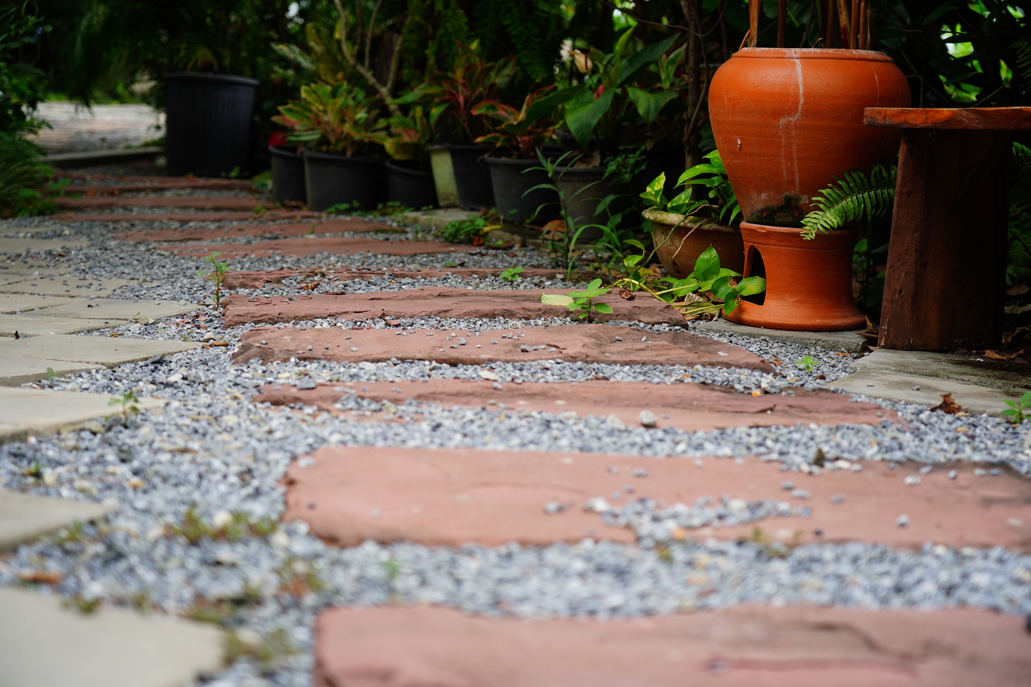 Garden pathway with red stepping stones and potted plants
