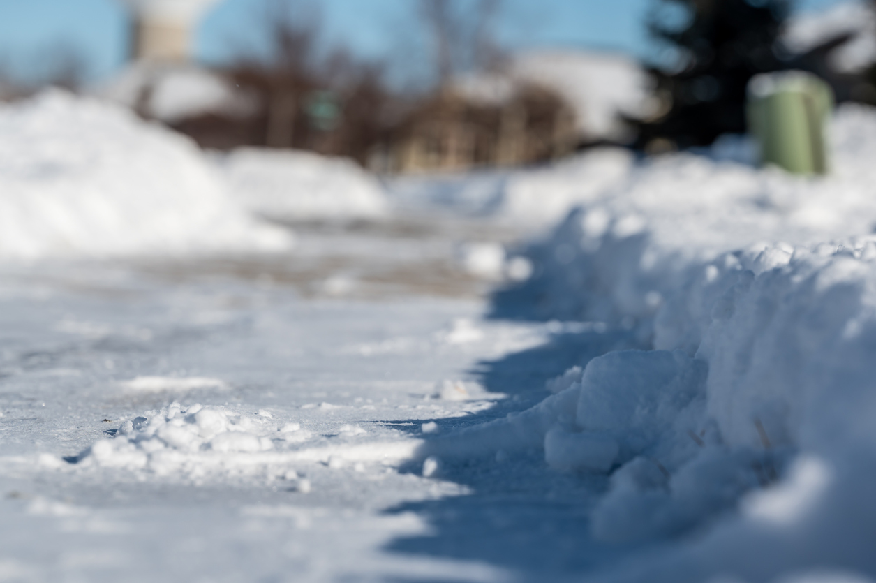 Snow-covered sidewalk with piled snow edges