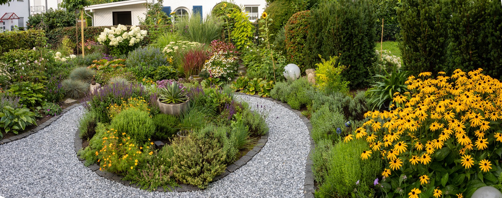 Circular gravel path through lush flowering garden