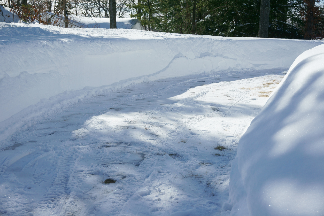 Snow-covered driveway with tall snowbanks in winter