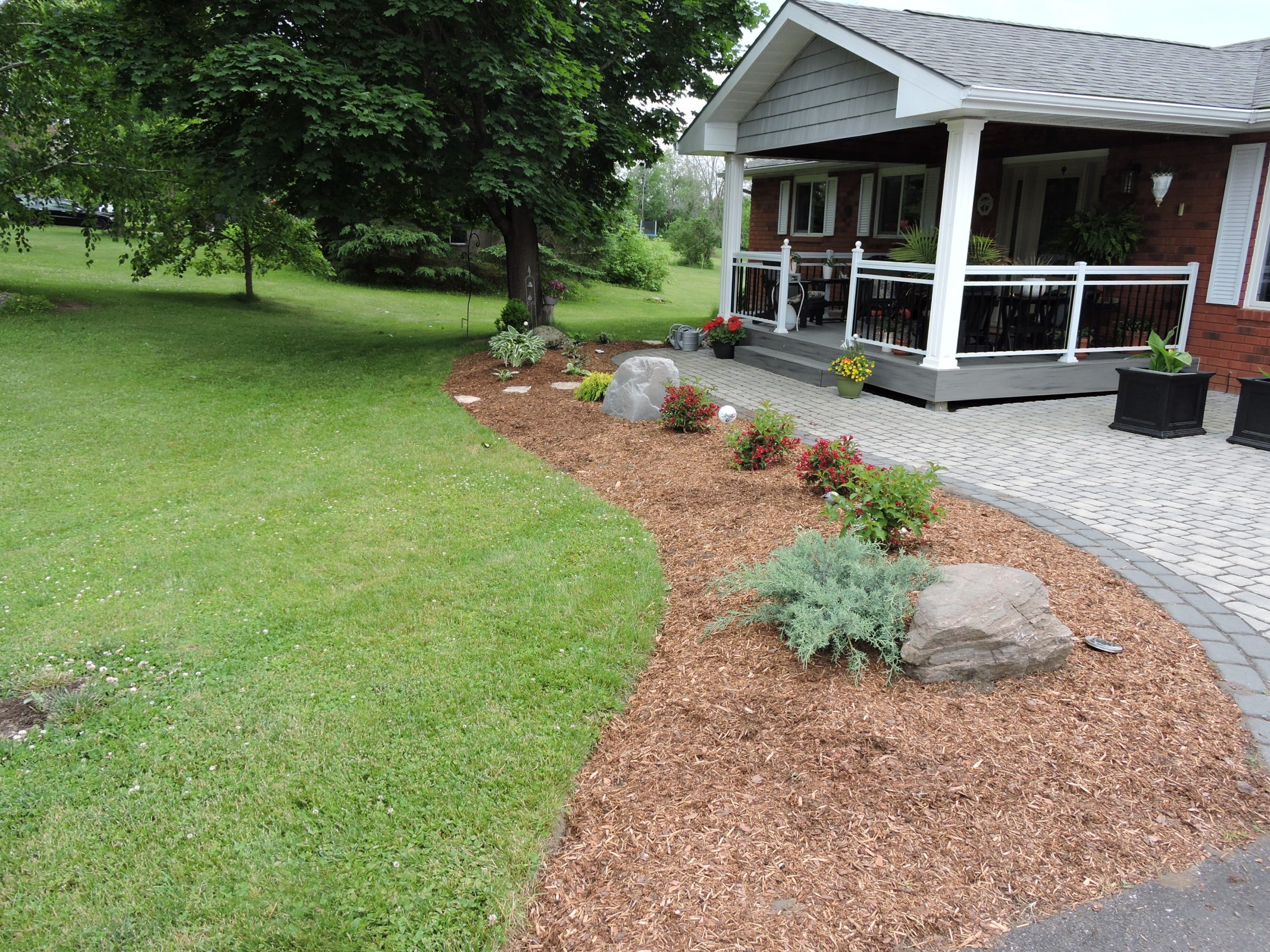 Landscaped front yard with porch and flower beds