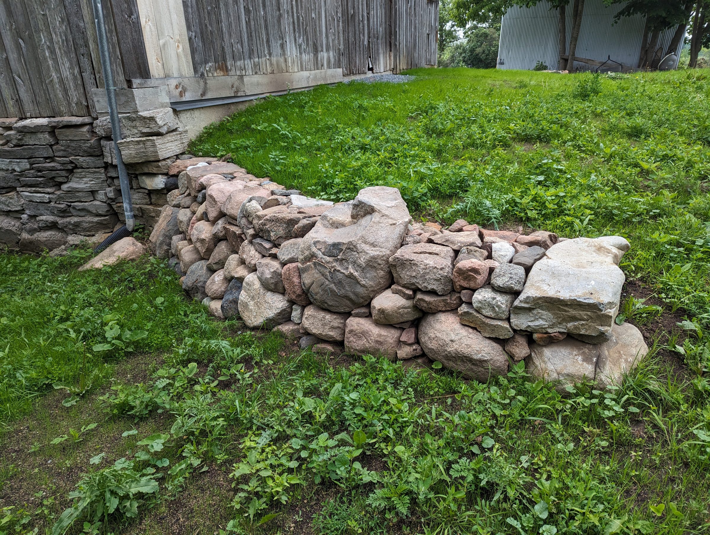 Stacked stone retaining wall beside rustic wooden barn